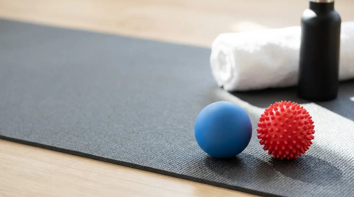 Massage balls on a yoga mat with a towel and water bottle